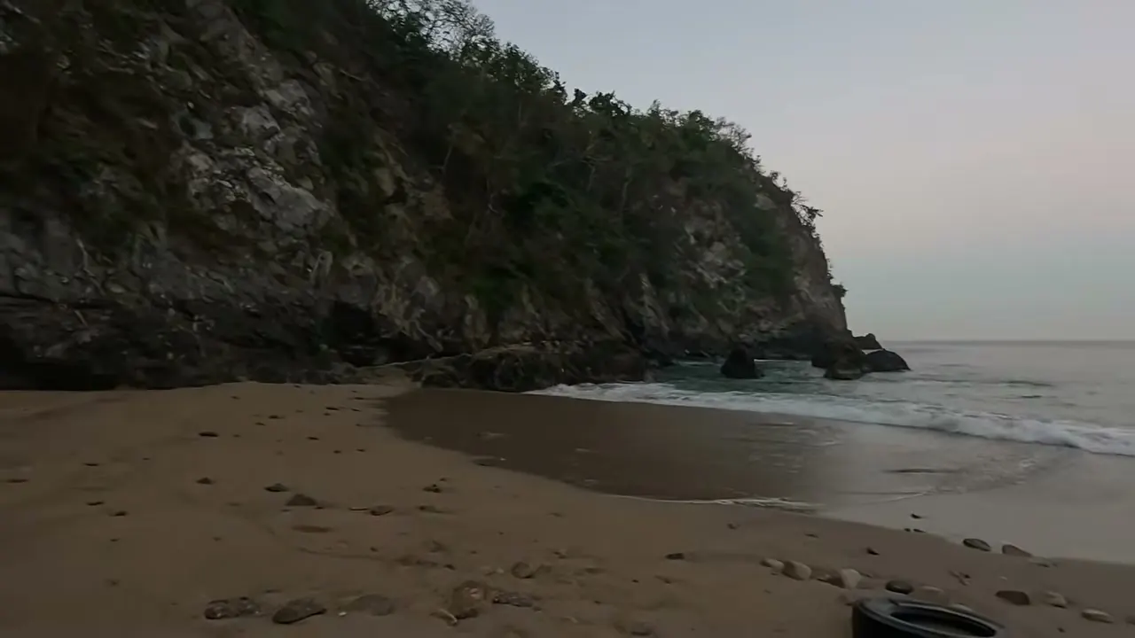 La playa al amanecer, con el cerro de roca a un lado
